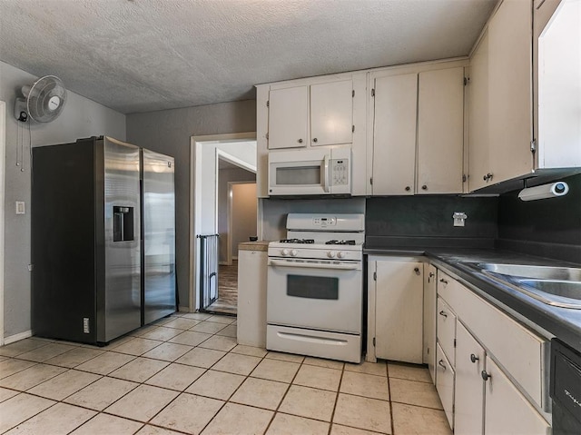 420 W Lincoln St, Purcell, OK 73080 - kitchen with dark countertops, light tile patterned flooring, white cabinets, a textured ceiling, and white appliances