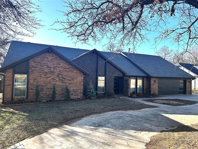 view of front of property featuring a garage, brick siding, driveway, and roof with shingles