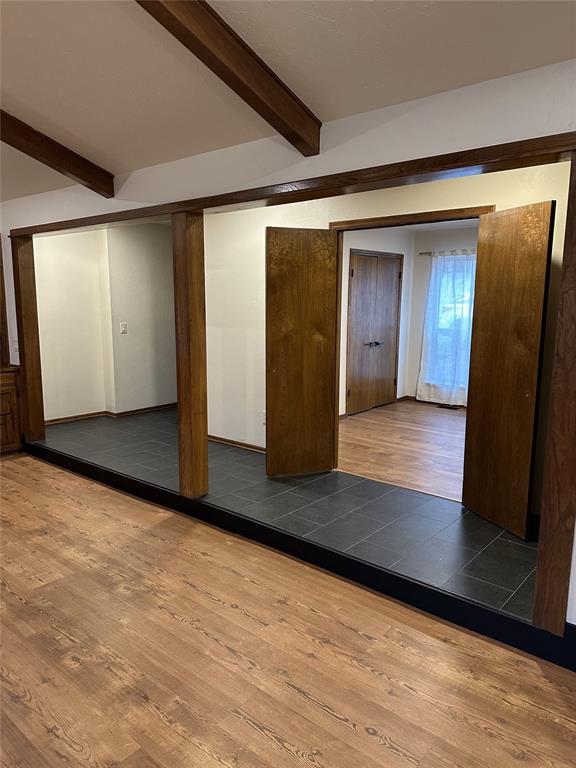 spare room featuring beam ceiling and wood finished floors