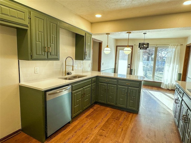 kitchen with dark wood-style flooring, green cabinets, a sink, dishwasher, and a peninsula