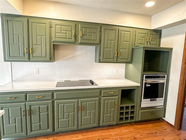 kitchen featuring light countertops, black electric cooktop, oven, and green cabinetry