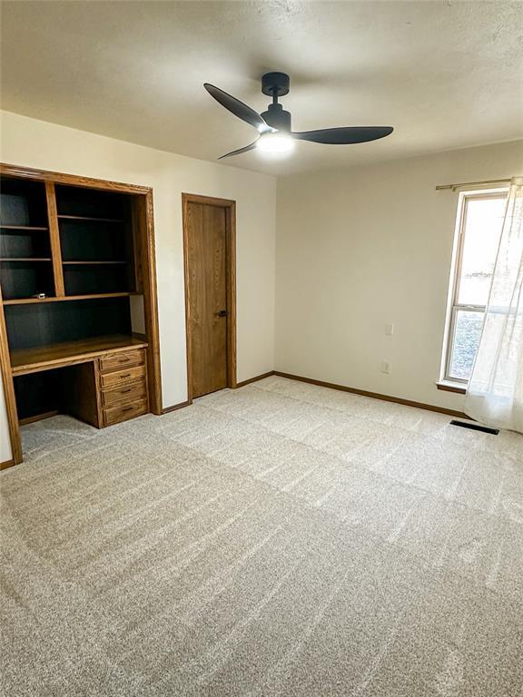 unfurnished bedroom with ceiling fan, baseboards, multiple closets, and light colored carpet