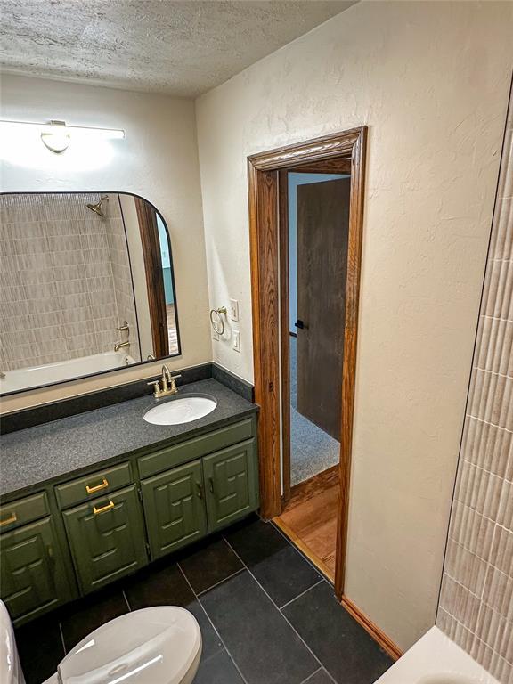 full bath featuring toilet, vanity, shower / tub combination, a textured ceiling, and tile patterned floors