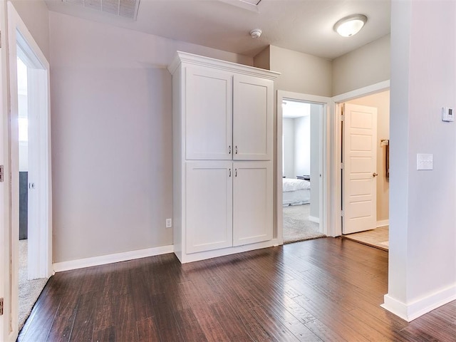 interior space with dark wood-style floors, visible vents, and baseboards