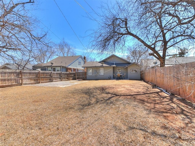 rear view of house with a lawn and a fenced backyard