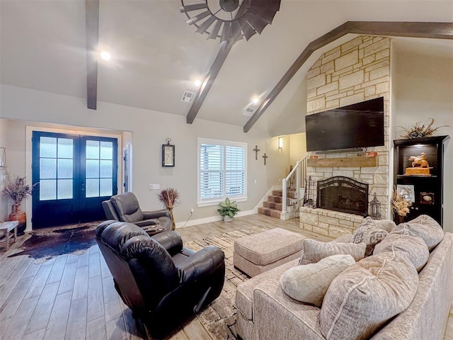 living area featuring visible vents, beamed ceiling, a fireplace, french doors, and wood finished floors