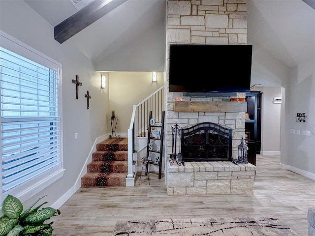 living room with stairway, wood finished floors, baseboards, vaulted ceiling with beams, and a fireplace