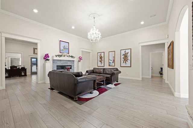 living room with light wood finished floors, baseboards, visible vents, a premium fireplace, and ornamental molding