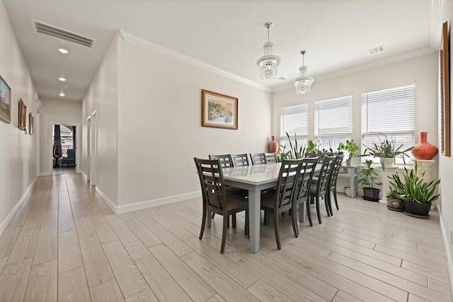 dining area featuring ornamental molding, light wood-type flooring, visible vents, and a notable chandelier