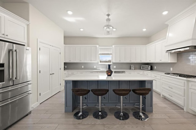 kitchen with high end refrigerator, a kitchen bar, white cabinets, and a center island