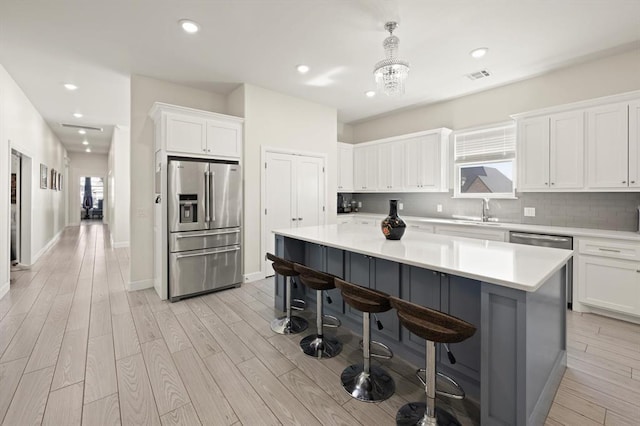 kitchen featuring a kitchen island, a sink, visible vents, stainless steel refrigerator with ice dispenser, and decorative backsplash