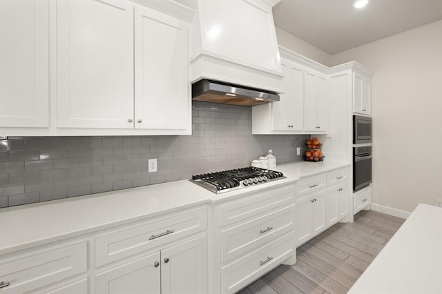 kitchen featuring stainless steel appliances, white cabinets, and light countertops