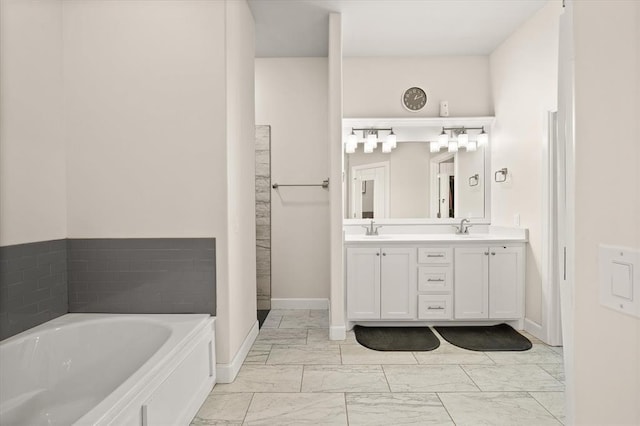 bathroom featuring a bath, marble finish floor, double vanity, and a sink