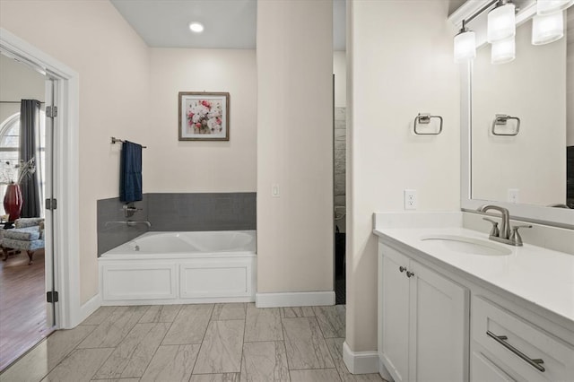 bathroom featuring vanity, baseboards, and a bath