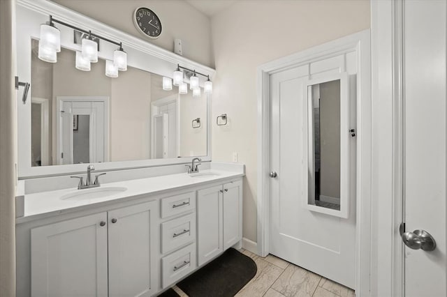 bathroom featuring marble finish floor, double vanity, and a sink