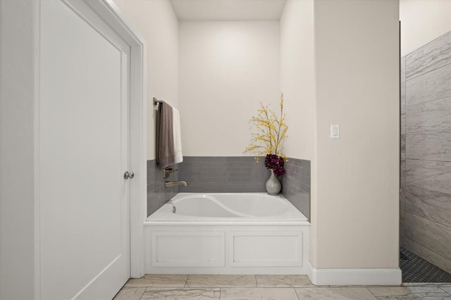 full bathroom featuring marble finish floor and a bath