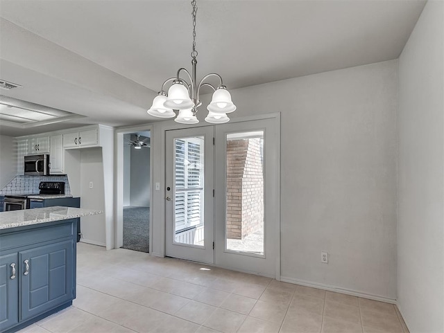 unfurnished dining area featuring light tile patterned floors, baseboards, visible vents, and ceiling fan with notable chandelier