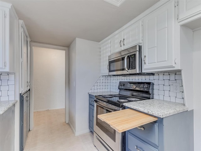 kitchen with light tile patterned floors, range with electric cooktop, white cabinets, backsplash, and stainless steel microwave