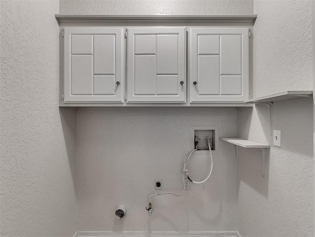 washroom featuring cabinet space, a textured wall, hookup for a gas dryer, hookup for a washing machine, and hookup for an electric dryer