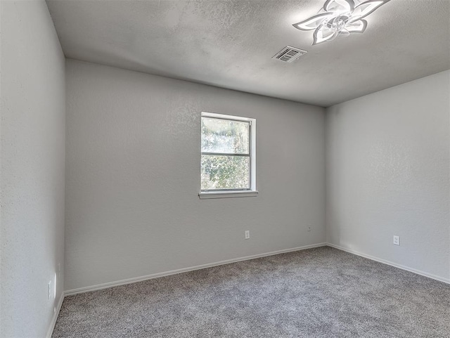 empty room with carpet floors, baseboards, visible vents, and a textured ceiling