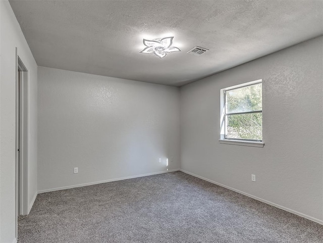 carpeted empty room featuring visible vents, a textured wall, a textured ceiling, and baseboards