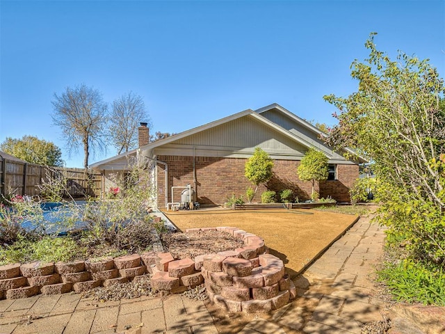 back of property featuring brick siding, fence, and a chimney