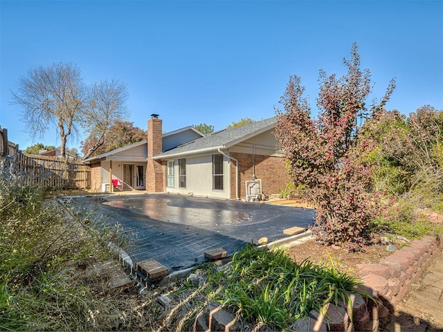 back of house featuring a patio area, a fenced backyard, a chimney, and brick siding