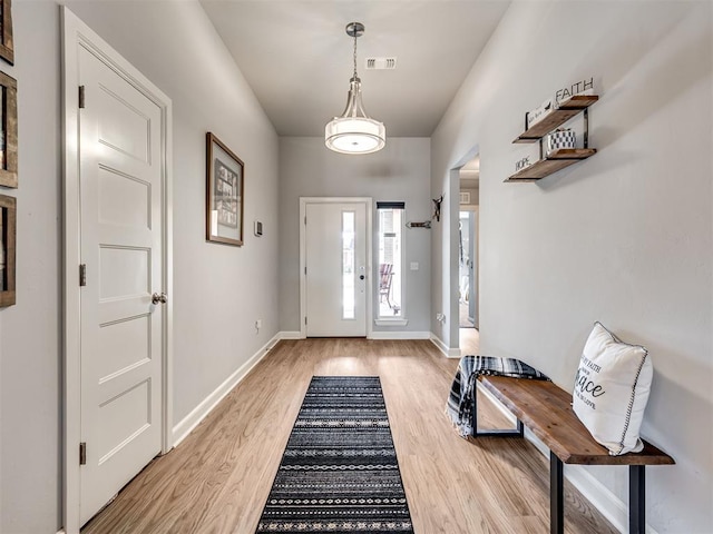 foyer entrance with baseboards, visible vents, and light wood finished floors