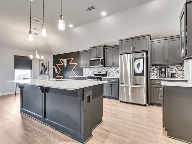 kitchen featuring lofted ceiling, stainless steel appliances, a sink, visible vents, and light countertops