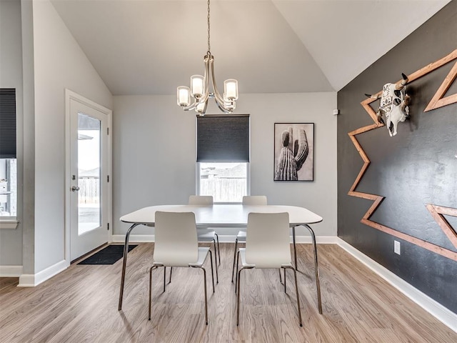 dining space featuring lofted ceiling, light wood finished floors, a notable chandelier, and baseboards