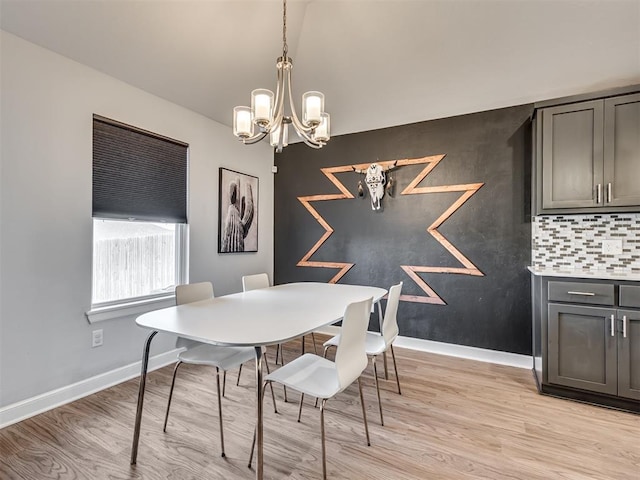 dining space with a chandelier, light wood-style flooring, and baseboards