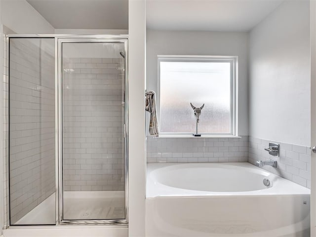 bathroom featuring a garden tub and a shower stall