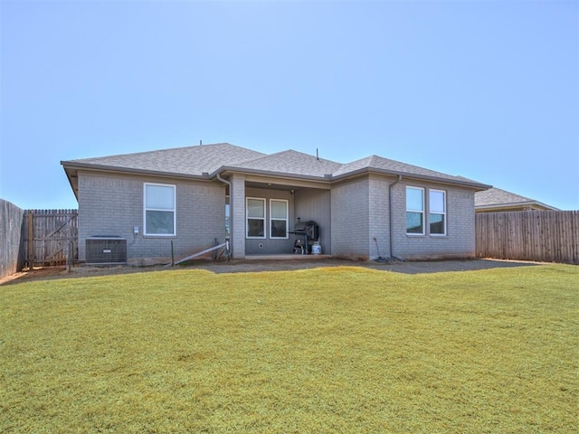 rear view of property with central AC, a yard, a fenced backyard, and brick siding