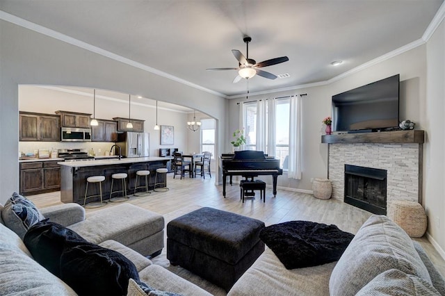 living room with light wood-style flooring, a fireplace, ornamental molding, and baseboards