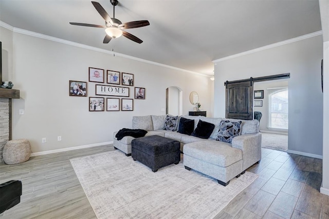 living area featuring arched walkways, a barn door, wood finished floors, and a ceiling fan