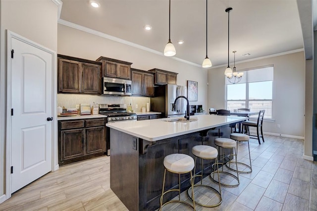 kitchen with a center island with sink, stainless steel appliances, light countertops, backsplash, and a sink