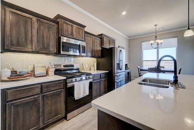 kitchen featuring appliances with stainless steel finishes, light countertops, a sink, and ornamental molding