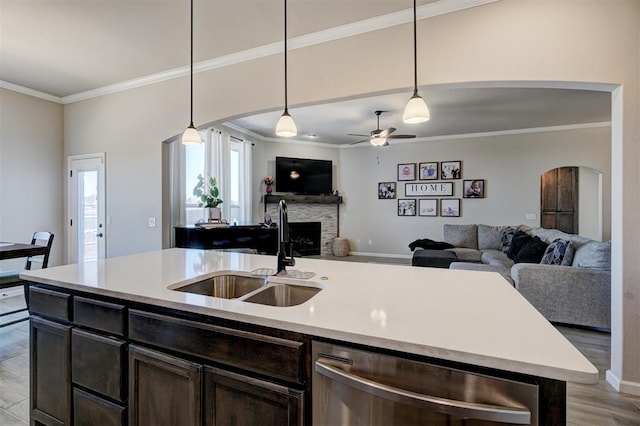 kitchen featuring arched walkways, a sink, open floor plan, stainless steel dishwasher, and ornamental molding