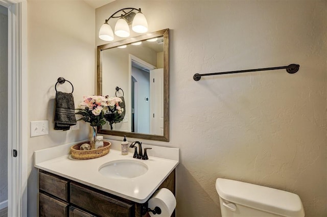 bathroom featuring a textured wall, vanity, and toilet