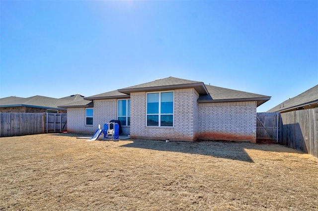 back of property featuring brick siding, a lawn, and a fenced backyard