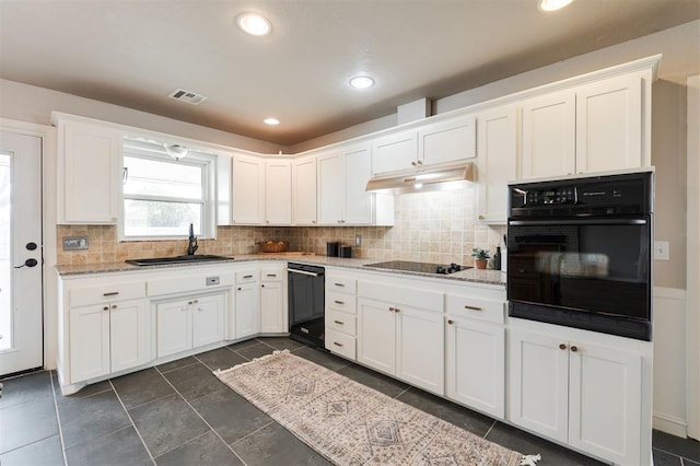 kitchen featuring visible vents, black appliances, under cabinet range hood, a sink, and white cabinets