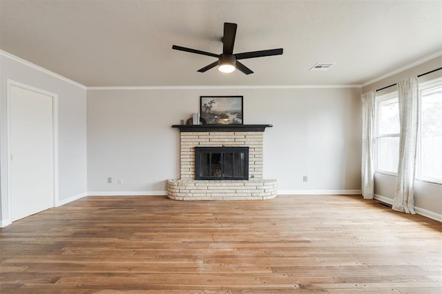 unfurnished living room with visible vents, ornamental molding, wood finished floors, baseboards, and a brick fireplace