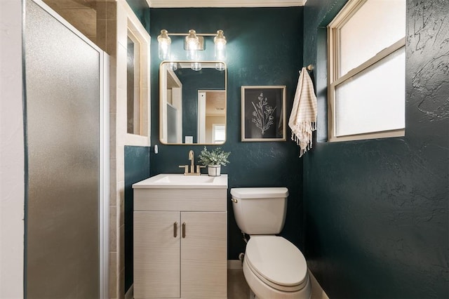 bathroom featuring toilet, a stall shower, vanity, and a textured wall