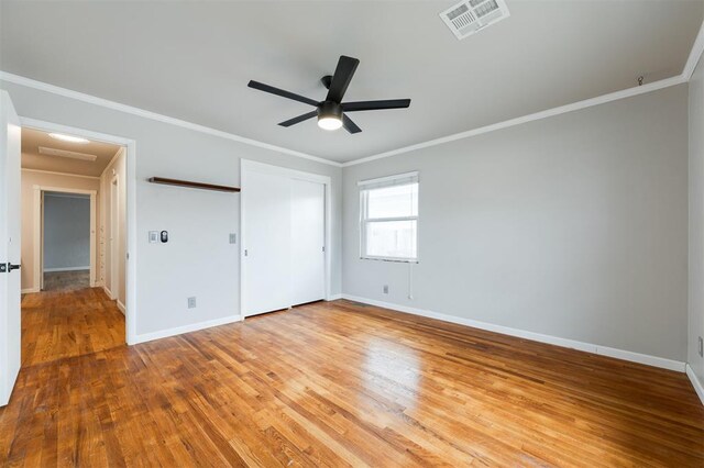 unfurnished bedroom featuring visible vents, baseboards, wood finished floors, and ornamental molding