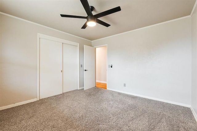 unfurnished bedroom featuring crown molding, baseboards, a closet, and carpet floors