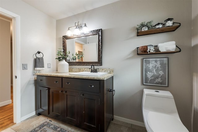 bathroom featuring baseboards, toilet, and vanity