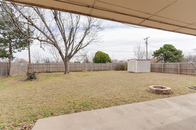 view of yard with a fenced backyard, a fire pit, an outdoor structure, and a shed