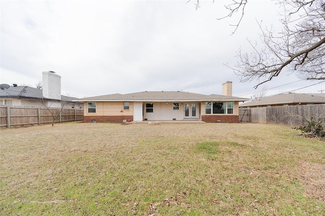 back of house with crawl space, a yard, brick siding, and a fenced backyard