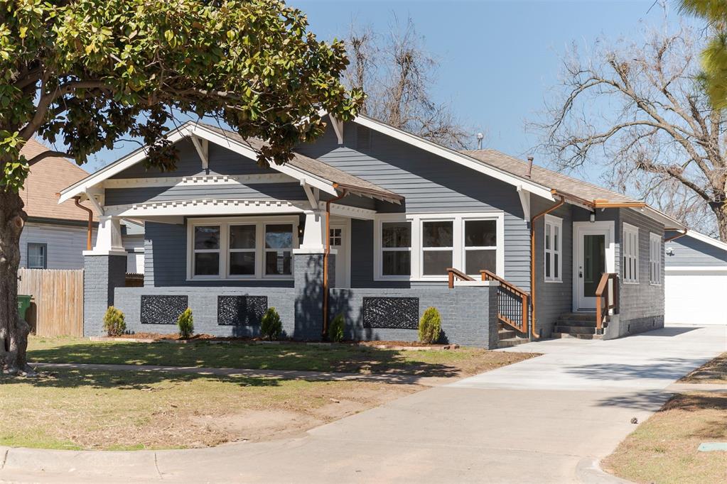 view of front of home with an outbuilding, a detached garage, fence, a front yard, and brick siding