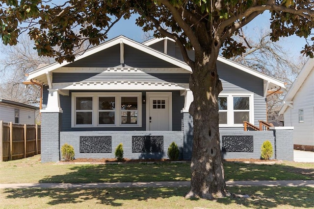 view of front of home featuring brick siding, a front lawn, and fence